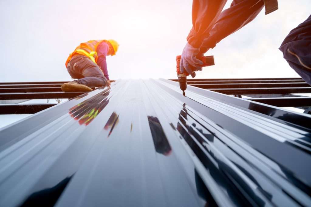 Roofing contractors installing metal panels on a commercial building in Spring Branch, TX.