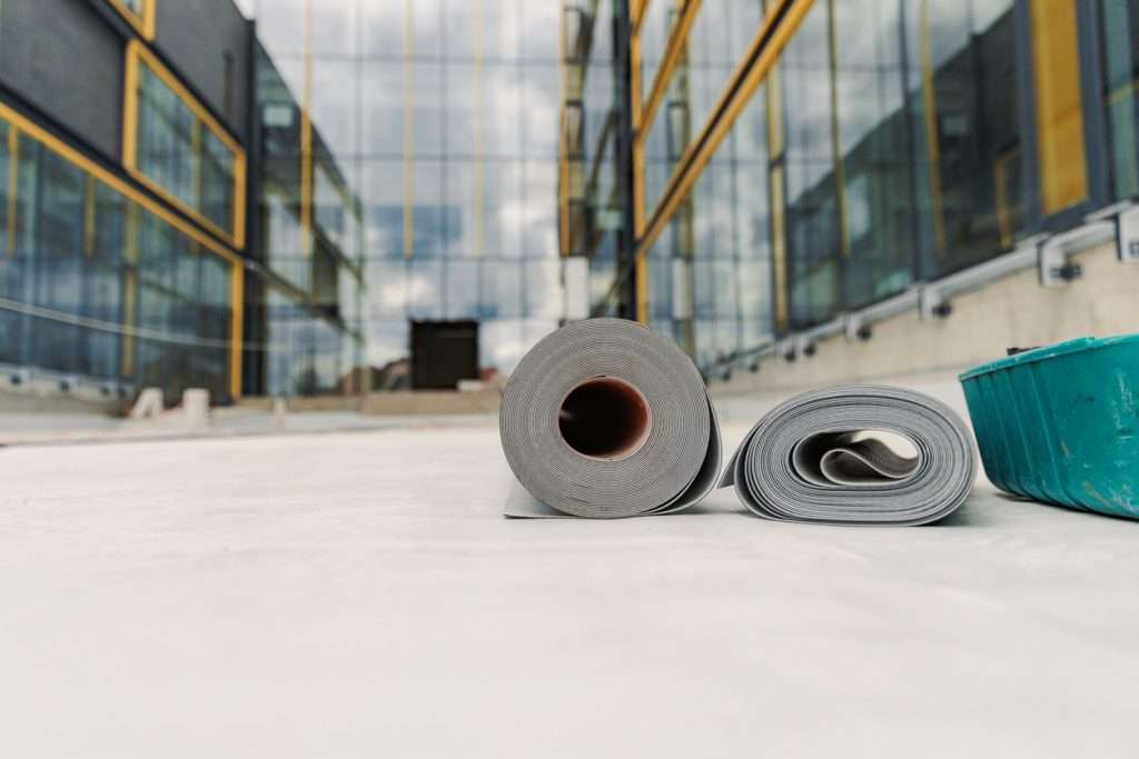 Rolls of EPDM roofing material and a container on a commercial building site, emphasizing roofing materials relevant to commercial roofing longevity.
