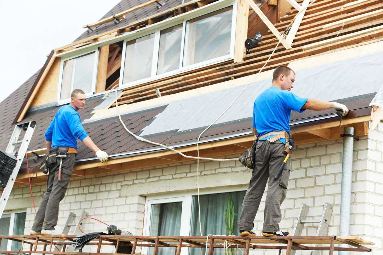 Two roofers working on a residential property, installing shingles and roofing materials, with a focus on quality roofing solutions for home improvement.