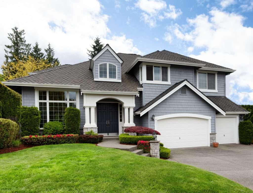 House with a gray shingle roof and well-maintained landscaping, showcasing a modern architectural style, relevant to roofing options and costs discussed on the page.