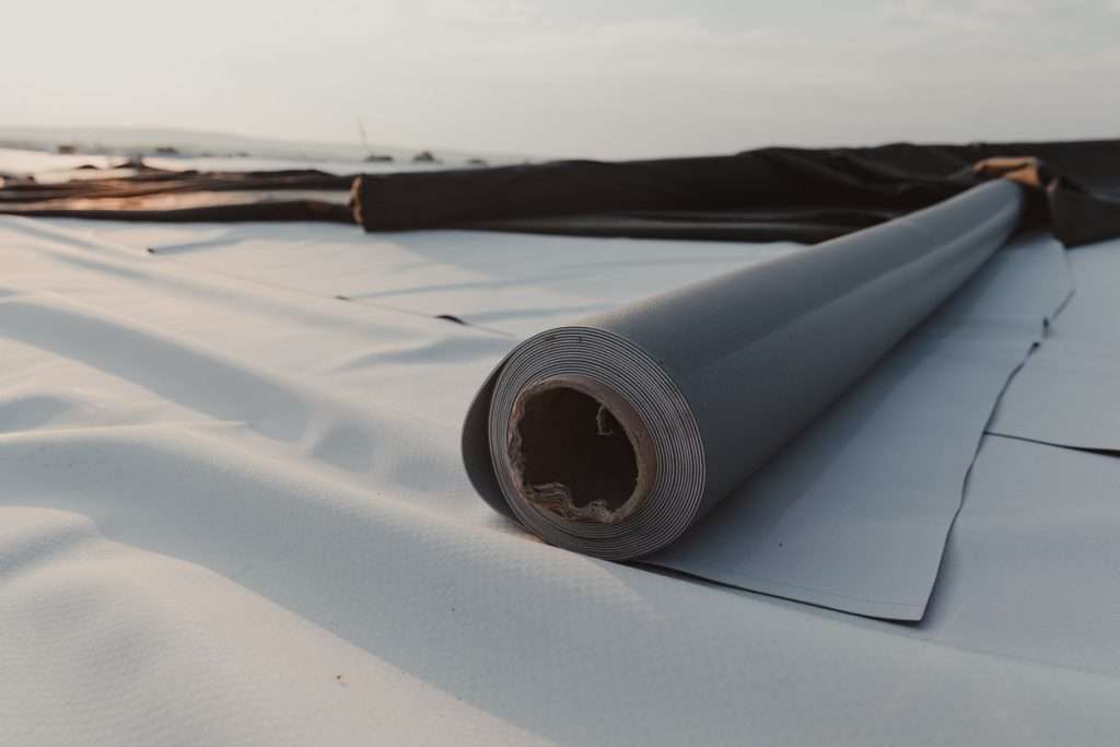 Roll of roofing material on a flat roof, showcasing installation process for commercial and industrial roofing solutions.