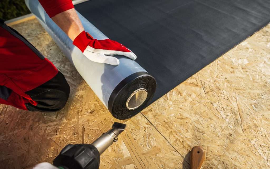 Professional roofer installing TPO roofing membrane on a commercial property, showcasing craftsmanship and high-performance materials for energy-efficient roofing solutions.