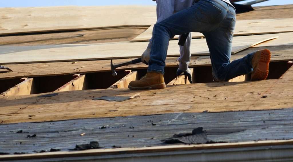 Worker repairing a roof with tools, demonstrating roofing installation and maintenance, relevant to budget-friendly roofing options.