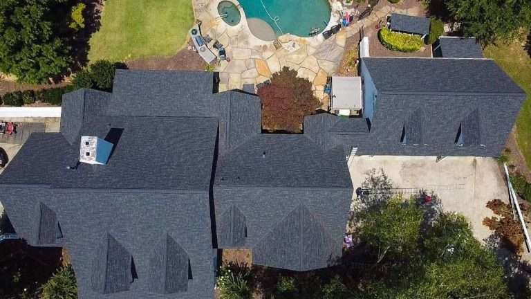 Aerial view of a residential property showcasing a new asphalt shingle roof, surrounded by a landscaped yard and pool area, emphasizing quality roofing installation by Artisan Roofing & Construction.