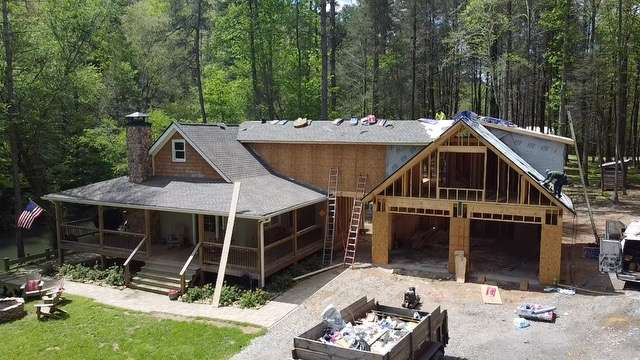 Roof replacement in progress on a residential home, showcasing construction materials and equipment, surrounded by trees, emphasizing the importance of specialized techniques for historical landmarks.