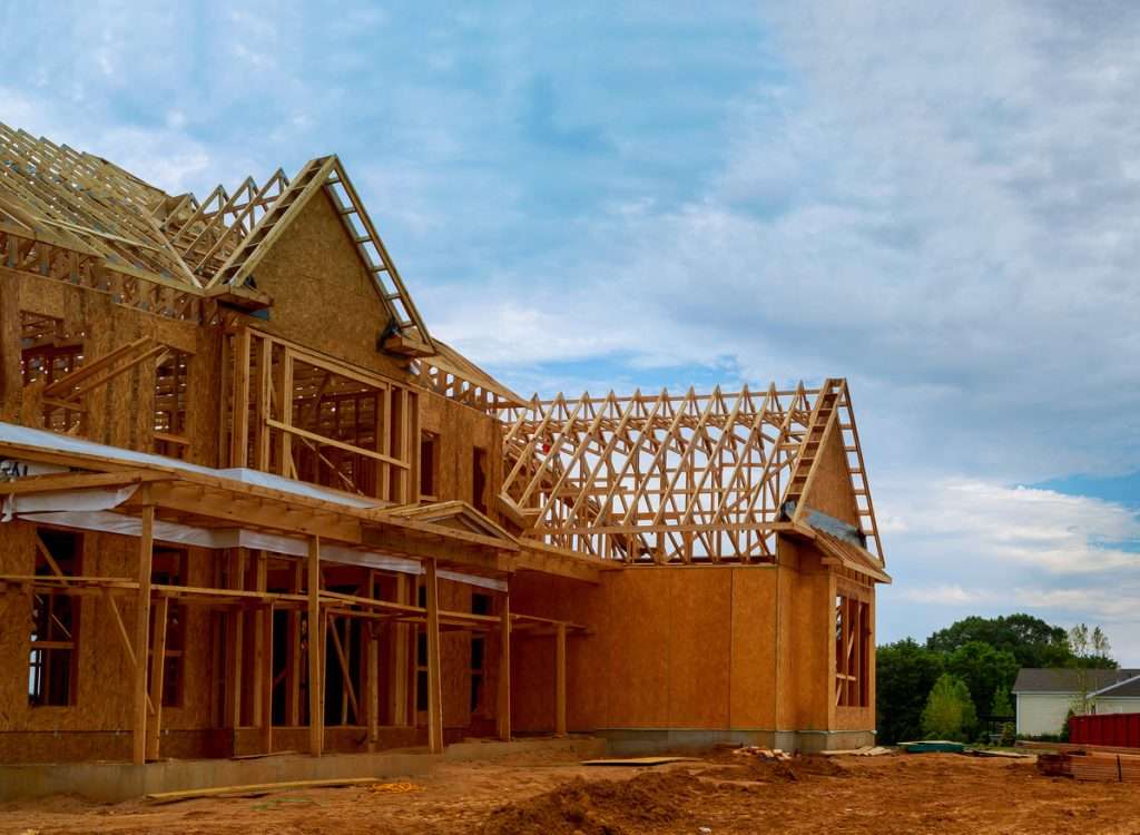 Construction of a new residential home with wooden framing and roof structure, showcasing craftsmanship and building progress relevant to Artisan Roofing & Construction's services.