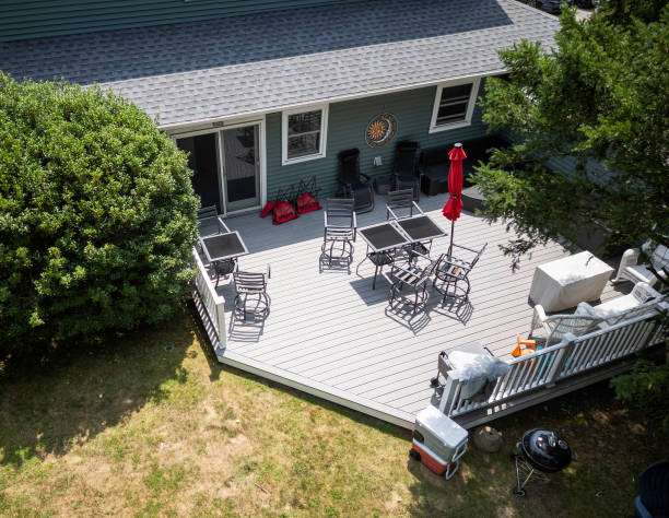 Deck installation featuring a spacious outdoor area with multiple seating arrangements, a red umbrella, and a barbecue grill, enhancing home comfort and aesthetics.