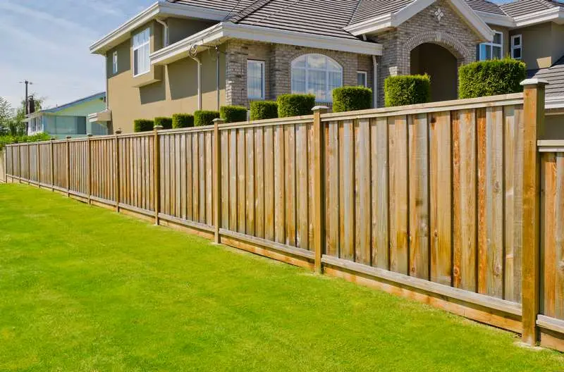 Wooden fence installation along a well-manicured lawn, enhancing property security and aesthetic appeal for residential homes.