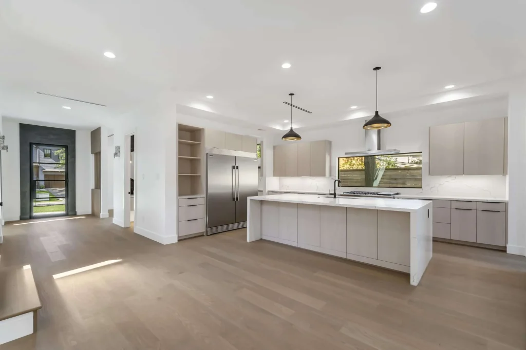 Modern kitchen interior featuring sleek cabinetry, stainless steel appliances, and a spacious island, emphasizing Artisan Roofing & Construction's expertise in kitchen remodeling.