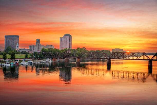 Augusta, GA skyline at sunset reflecting on the Savannah River, showcasing vibrant colors and urban architecture, emphasizing the city's charm and community.