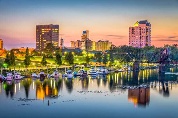 Augusta, GA skyline at sunset with waterfront park, modern buildings, and boats reflecting in the Savannah River, highlighting the city's blend of tradition and progress.