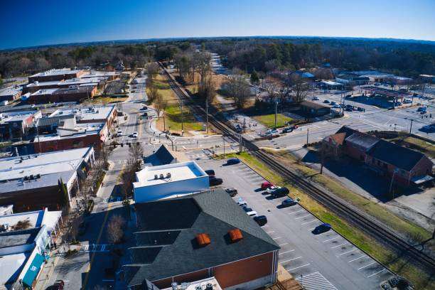Aerial view of Buford, GA, showcasing downtown streets, commercial buildings, and nearby parks, highlighting the city's blend of urban and small-town charm, relevant to Artisan Roofing & Construction's services in home renovations.