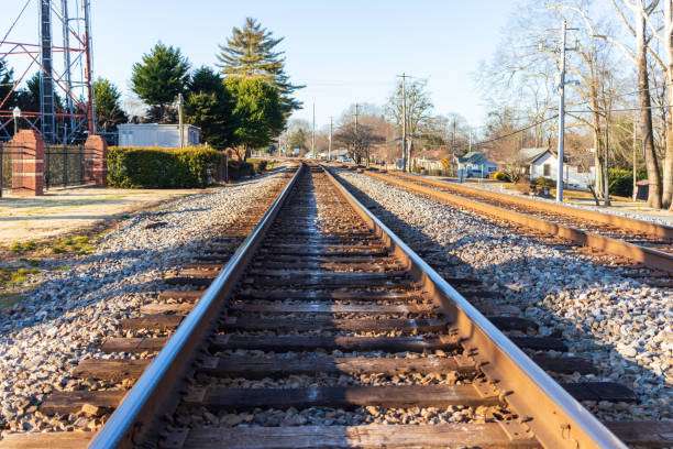 Railroad tracks leading through a suburban area in Buford, GA, surrounded by trees and homes, highlighting the community's growth and accessibility.