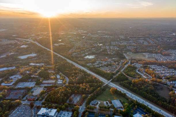 Aerial view of Cumming, GA at sunset, showcasing residential neighborhoods, highways, and natural landscapes, highlighting the community's growth and scenic beauty.