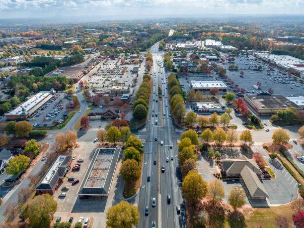 Aerial view of a busy road in Cumming, GA, showcasing commercial buildings, parking lots, and tree-lined streets, reflecting the city's growth and community development.