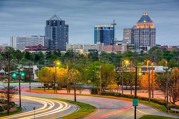Greensboro, GA skyline at dusk with modern buildings, illuminated streets, and lush greenery, reflecting the area's blend of historic charm and contemporary living.
