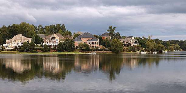 Lakefront homes along the serene waters of Lake Oconee, showcasing luxury architecture and lush greenery, reflecting the elevated living standards and construction expertise of Artisan Roofing & Construction.