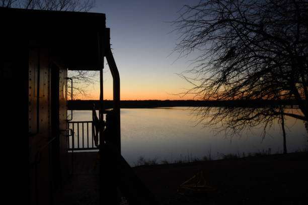 Sunset view over Lake Oconee, GA, featuring silhouette of lakeside structure and trees, highlighting serene waterfront living.