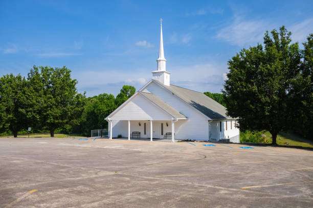 White church building with a tall steeple surrounded by trees, located in Cleveland, GA, reflecting the community-oriented atmosphere emphasized by Artisan Roofing Construction's services.