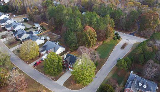 Aerial view of residential neighborhood in Flowery Branch, GA, showcasing homes and surrounding trees, emphasizing community and quality living.