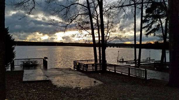 Scenic view of a lake at sunset with wooden docks and trees, highlighting Greensboro's charm and lakefront community lifestyle.