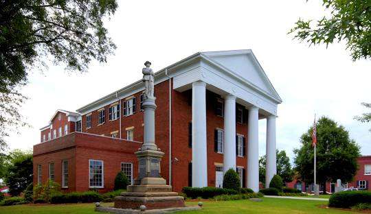 Historic building in Greensboro, GA, featuring classic architecture, columns, and a statue in front, representing the town’s charm and heritage.