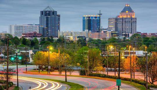 Greensboro, GA skyline at dusk featuring modern architecture, city lights, and tree-lined streets, representing the blend of historic charm and contemporary living.